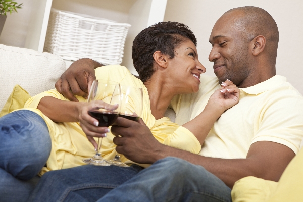 A happy African American man and woman couple in their thirties sitting at home together smiling and